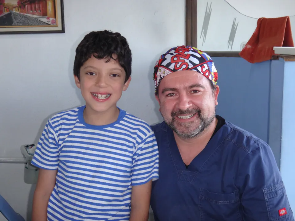 Niño sonriendo junto a su odontólogo en la clínica