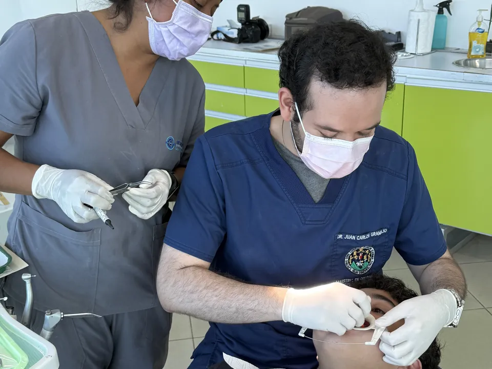 Odontólogo y asistente revisando los dientes de un joven paciente